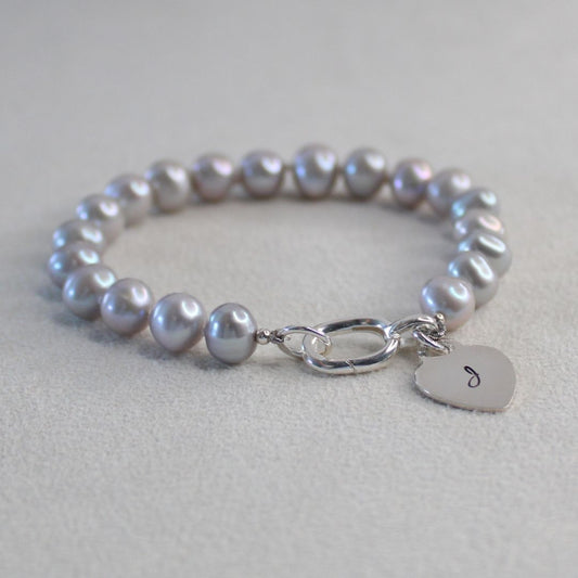 Grey Pearl bracelet with a silver heart initial charm on a soft background